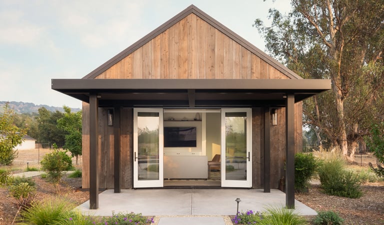 Small pool house made with mixed materials and white hinged doors